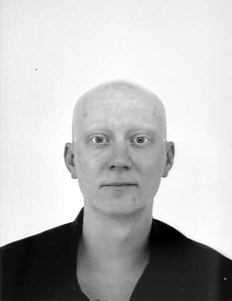 Portrait of Jan Borreck in black and white. He is looking straight into the camera, wearing a bald head and a black shirt.