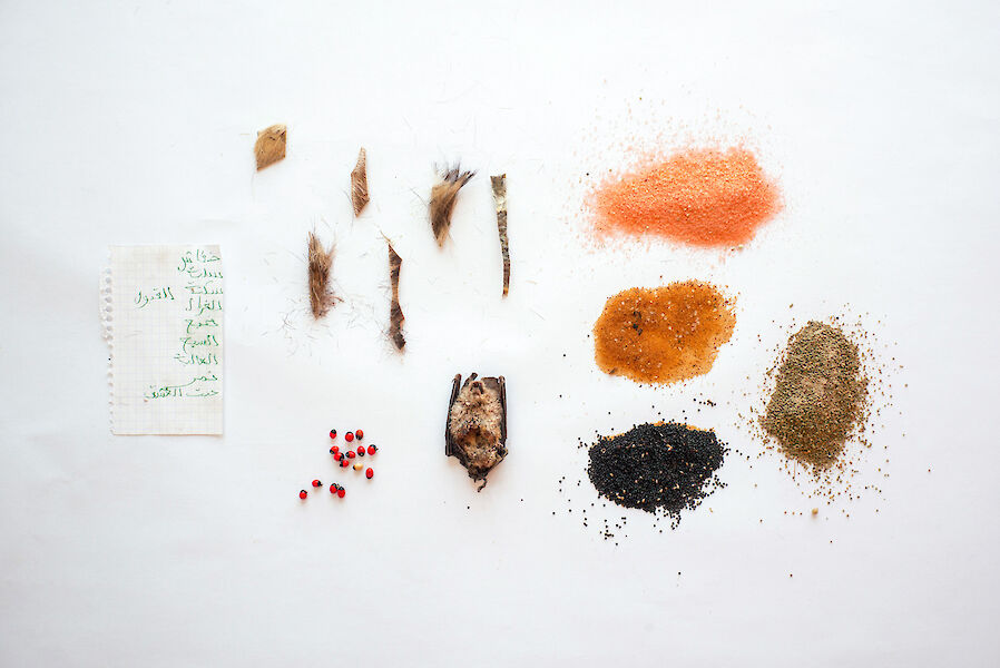Flatlay from above: various spices, fur, a bat and a handwritten note.