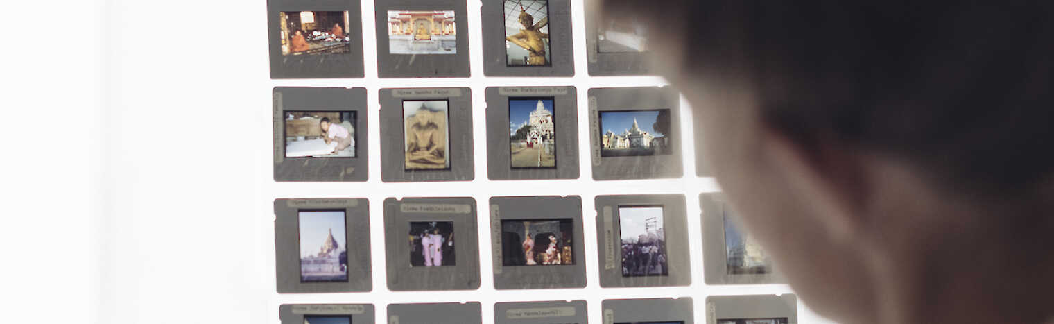 Eine Person hält ein Raster mit Diapositiven vor ein Fenster.