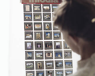 Eine Person hält ein Raster mit Diapositiven vor ein Fenster.  