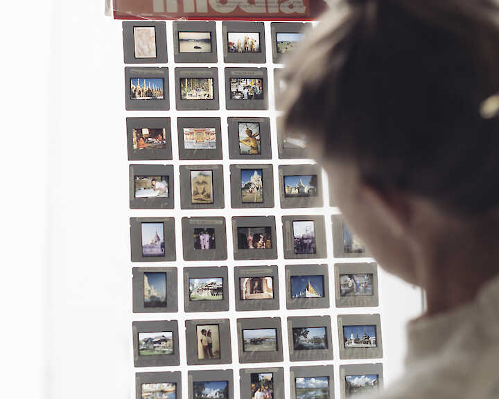 Eine Person hält ein Raster mit Diapositiven vor ein Fenster.  