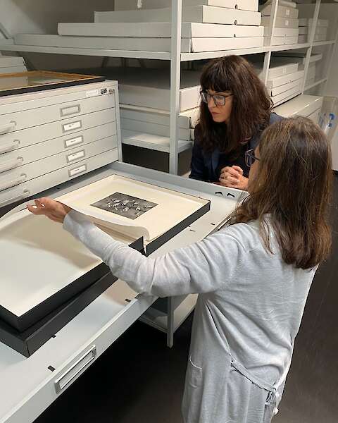 Elena Efeoglou beigt sich über einen Abzug, der in einer Archivmappe liegt.