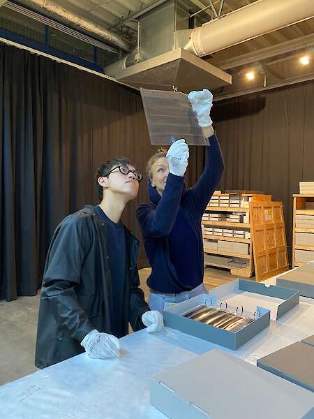 Jimmi Wing Ka Ho betrachtet mit Lucia Halder Negative in einer Hülle