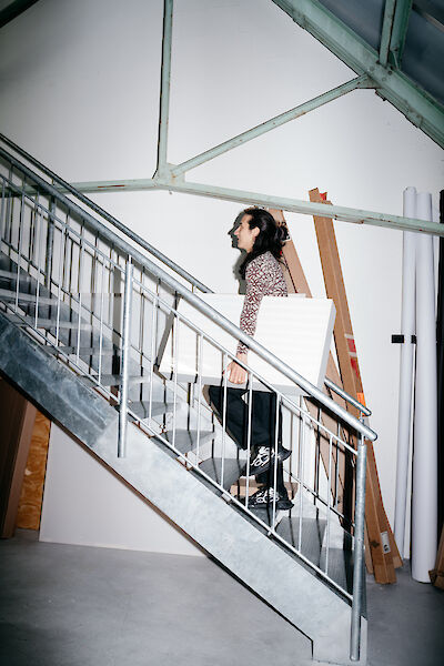 Nathan Ishar carries a canvas up the stairs in the studio.