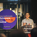 Heide Häusler steht an einem Rednerpult. Hinter ihr steht auf einem Sticker "Internationale Photoszene Köln Festival"