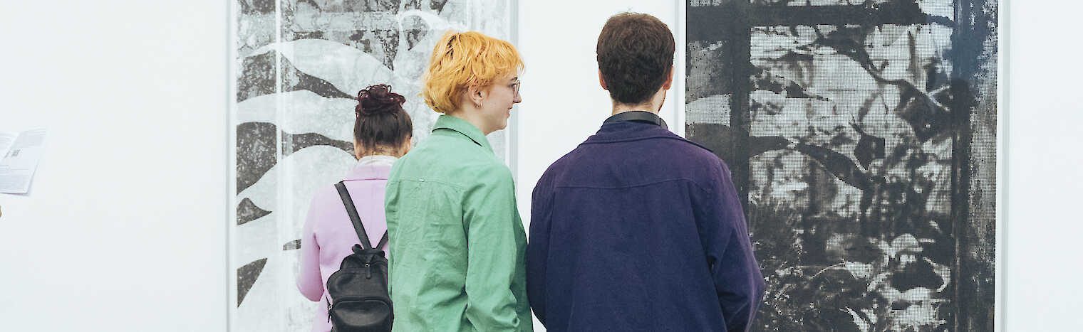 Besucher in einer Galerie, die vor großformatigen Fotografien stehen.