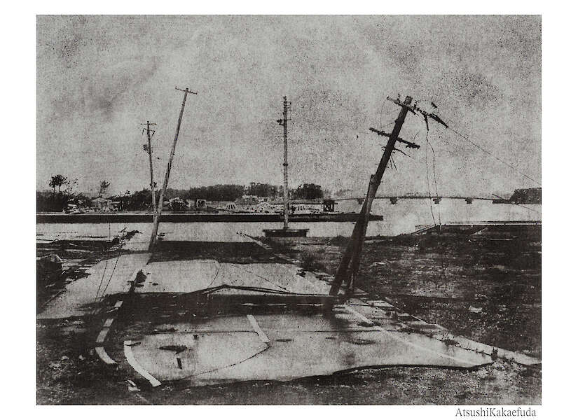 Ein verwittertes Foto zeigt eine beschädigte Straße mit umgestürzten Strommasten.